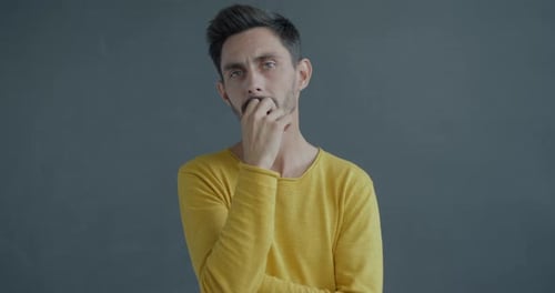 Retrato em câmera lenta de um jovem sério olhando para a câmera com a atenção levantando a sobrancelha tocando