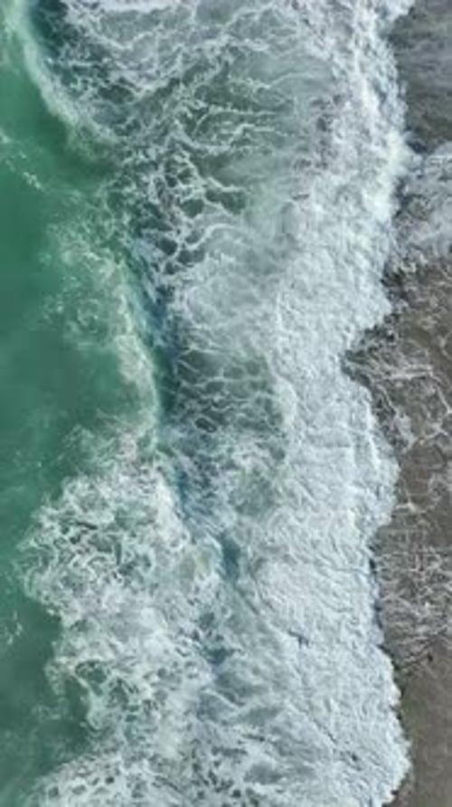 Vertical Video Aerial View of Stormy Mediterranean Waters With Crashing Waves and White Foam Flying
