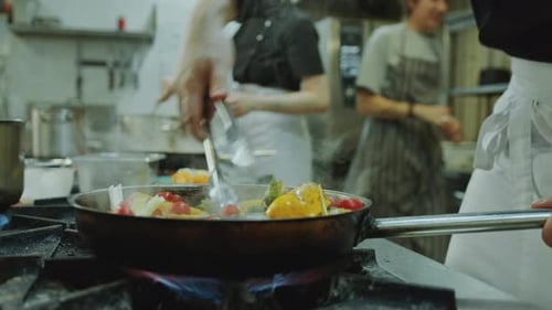 Chef Cooking Fish and Vegetables in Kitchen