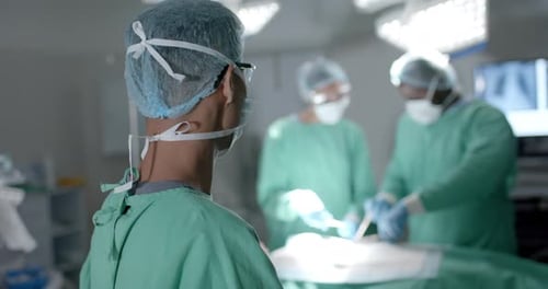 Portrait of diverse surgeons with face masks during surgery in operating room in slow motion