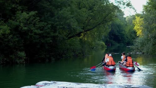 People are Floating Down the River on a Raft They are Being Overtaken By a Girl on a Wooden Canoe