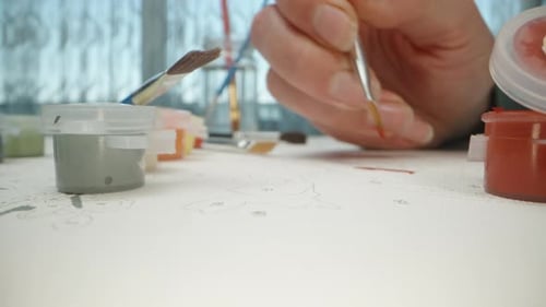 The girl draws a picture by numbers, she paints it orange. Dolly Slider extreme close-up