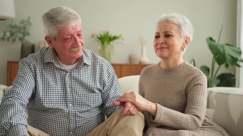Senior Couple Holding Hands on Sofa Lovingly