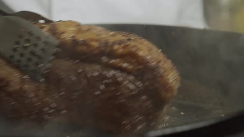 Frying meat steak inside frying pan. Close up slow motion shot.