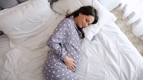 Pregnant Woman Resting Comfortably in Bed at Home