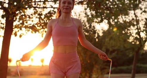 Happy woman jump rope outdoors in autumn park