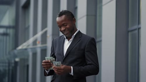 Happy Middle Aged African American Businessman Counting Money and Putting Them Into Suit Pocket