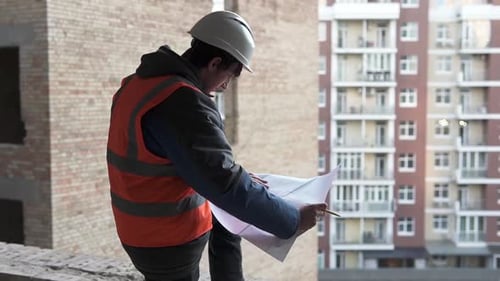 A construction engineer is looking at working drawings of a high-rise building.