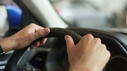 Closeup Cropped Shot of Unrecognizable Male Customer Testing New Car at Dealership Holding Steering