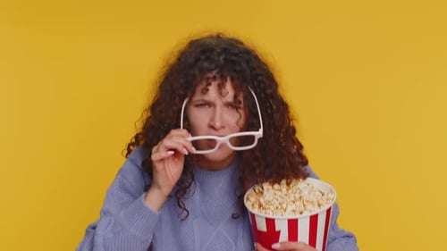 Femme excitée dans des lunettes 3D mangeant du pop-corn et regardant une série télévisée intéressante, un jeu de sport, un film