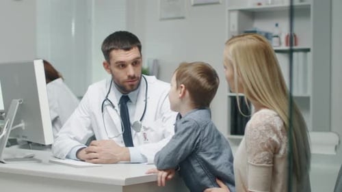 At Doctor's Office. Well Natured Male Doctor Talks and Jokes with Little Boy and His Mother. In Slo