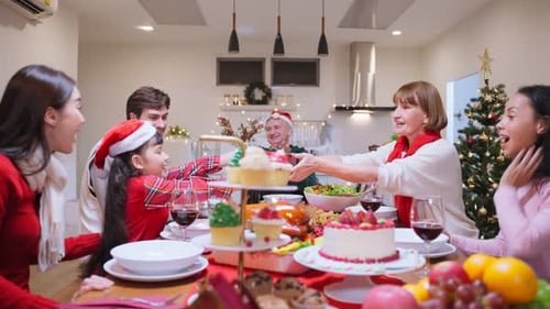 Family Gathering around Christmas Dinner Table Exchanging Gifts