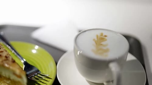 Cup of Cappuccino and Delicious Sweet Cake on Table in City Coffee Shop in Morning Closeup View
