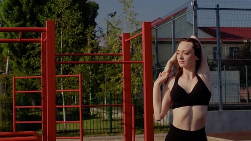 Athletic Woman Stretching Arms Outdoors in Sunlight