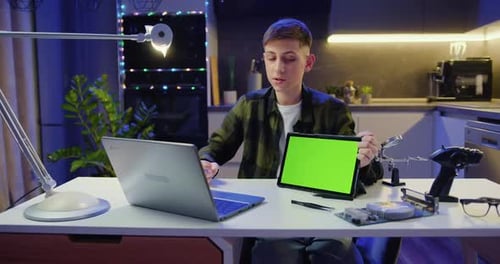 Chico atractivo que usa una computadora portátil trabajando en una videoconferencia. Tableta para adolescentes con pantalla verde