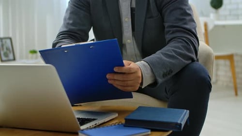 Man Writing Notes on Blue Clipboard in Office Setting