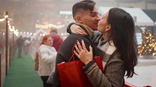 Loving Young Couple Kissing and Embracing on Christmas Night in City