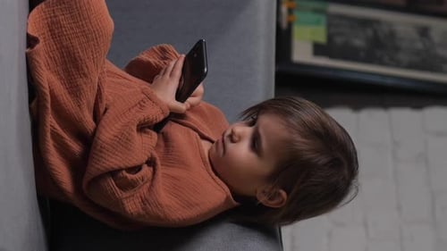 Child Lying on Couch Using Smartphone