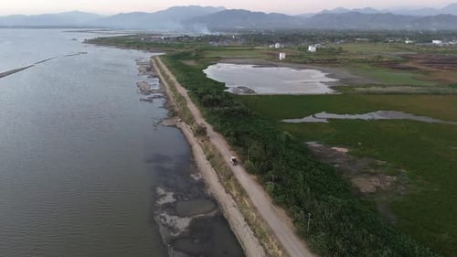 Aerial view of vehicles driving on a road crossing the Limboto Lake