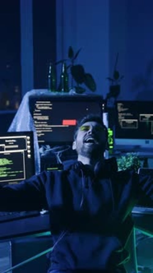 Man Celebrating at Multiple Computer Monitors at Night
