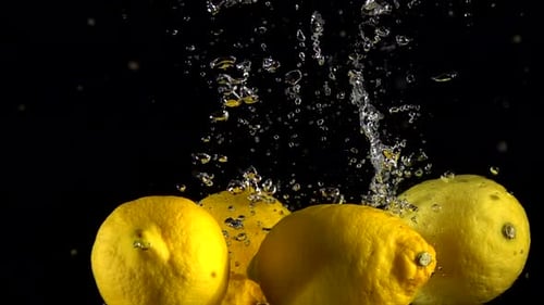 Lemons Dropping Into Water on Black Background