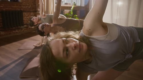 Gruppe von Frauen, die Warrior-Asana-Variationen im Loft Yoga Studio machen