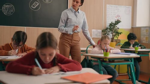 Caucasian Woman Teacher in Elementary School Teach Children Class Kids Writing Task in Classroom
