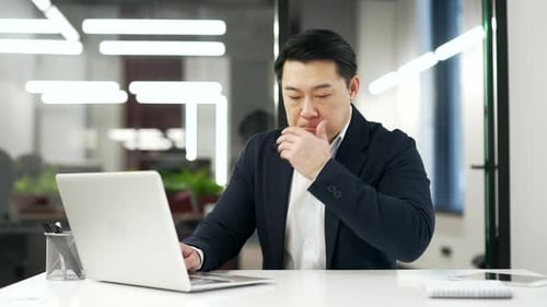 Asian businessman suffering from nauseous, wants to vomit while working on laptop sitting at desk