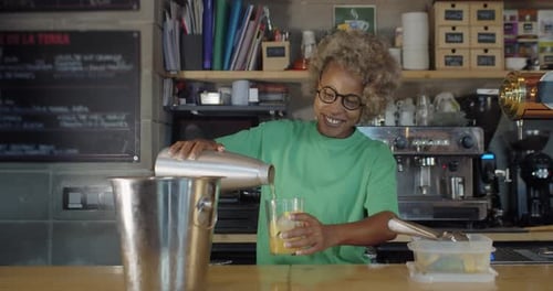 Happy African American Woman Waitress Serving a Cocktail or Drink in a Pub