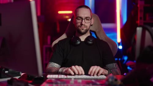 Young Man Typing at Computer Desk at Night