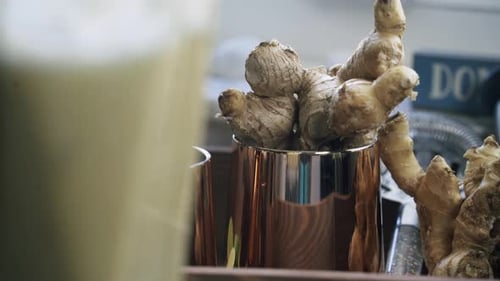 Nice shot of ginger being blended with a cluster of fresh ginger inside of a copper colored cup