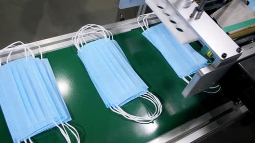 Machine Stacks Finished Masks in Pile on Green Conveyor