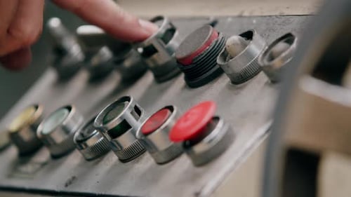A factory worker operating knobs and dials on a metal grinding