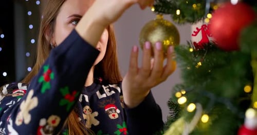 Woman Decorating Christmas Tree with Golden Ornament