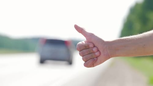 In the Foreground a Man's Hand Honking Passing Cars