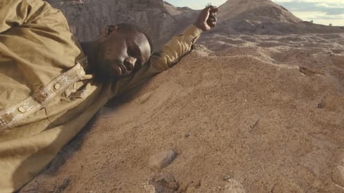African American Man Lying on His Side on Sand in Desert