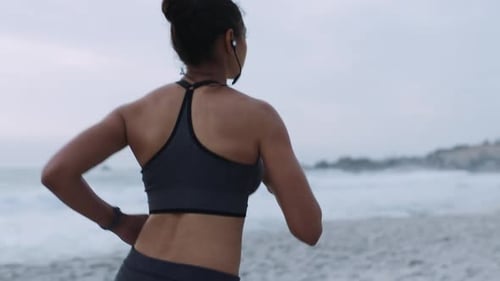 Beach running, woman and headphones of a runner by the ocean doing exercise with music