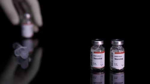 Hand Placing Covid Vaccine Vials Beside Syringe