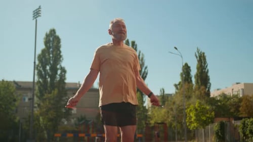 Caucasian Elderly Man Skipping with Jumping Rope at City Stadium Physical Activity Jump Warmup
