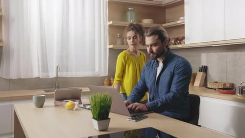 Man and Woman Using Laptop at Kitchen Table