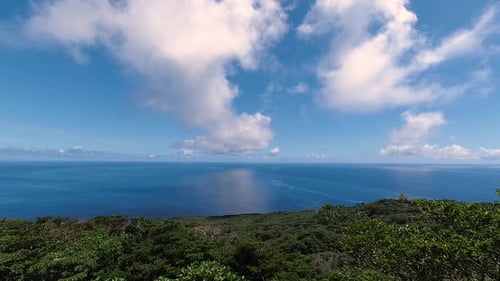 Schnell bewegender Wolken-Zeitraffer über offenem blauem Ozean mit Reflexionen von Wolken im Wasser mit Insel im