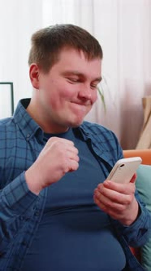 Man Cheers at Home after Good News on Phone
