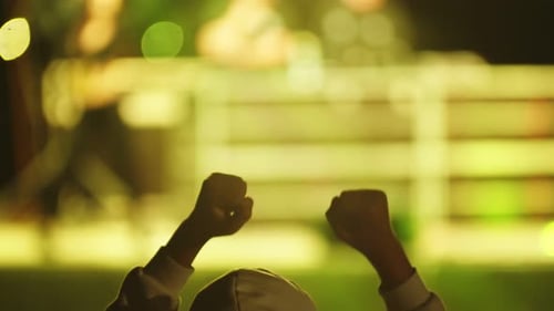 Male Fan in Hoodie Dances at a Rock Concert Raising His Hands Up