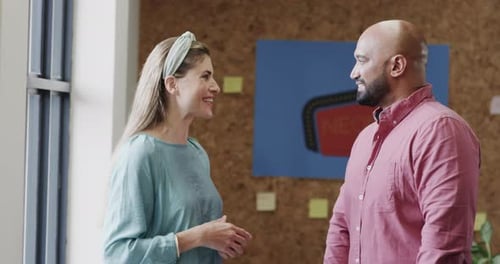 Two happy diverse creative designers in discussion in casual office, slow motion