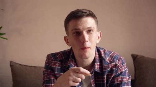 Man Eating Food and Watching TV at Home