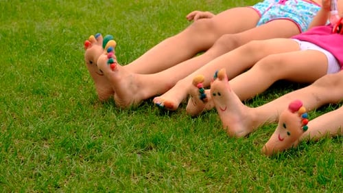 Children with Painted Toes Lying on Green Grass