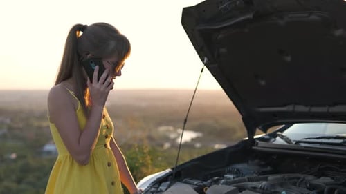 Young Female Driver Talking on Mobile Phone Standing Near Her Car with Open Hood Having Engine