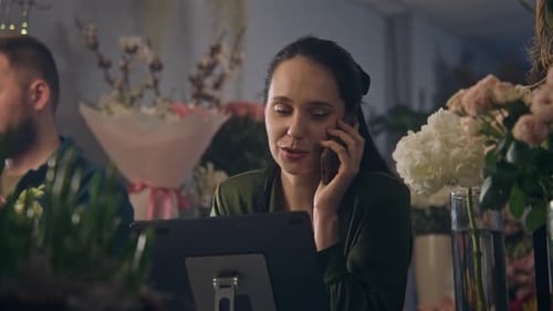 Female Florist Talks By Phone with Customer and Uses Tablet