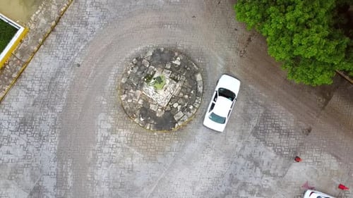 Drohnenaufnahme von oben nach unten vom Kreisverkehr mit vorbeifahrendem Auto und Motorrad