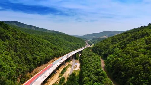 Scenic highway crossing lush green hills. A highway winds through lush hills under a bright blue sky